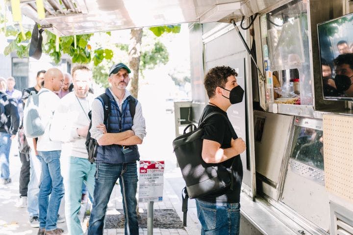 a group of people standing around a food truck